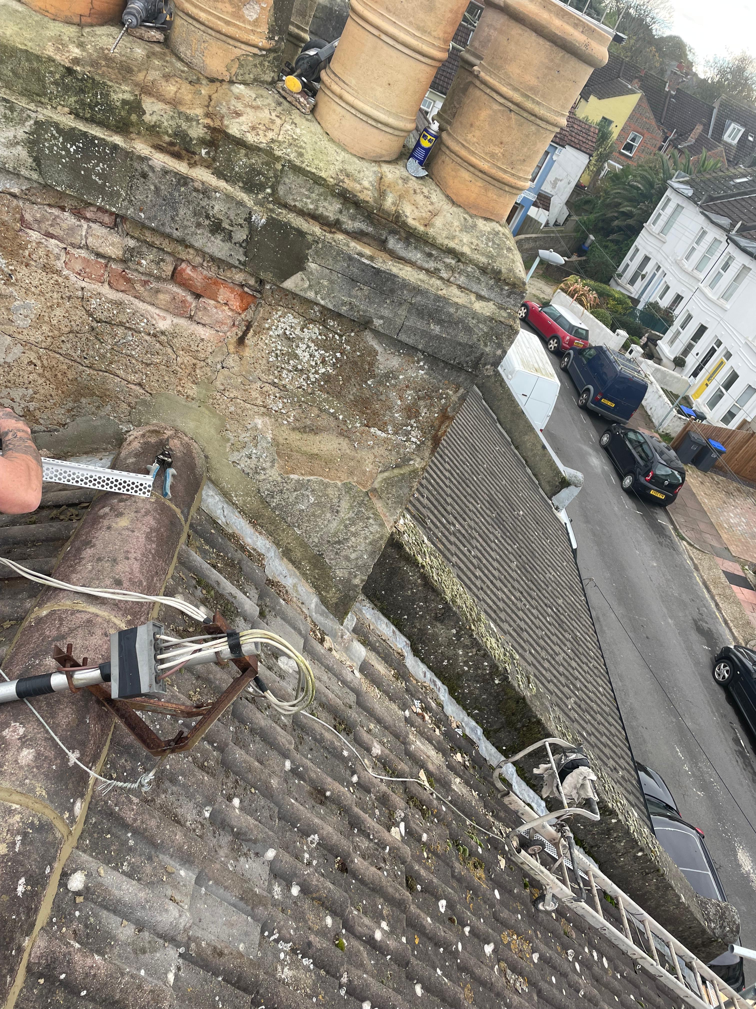Weathered chimney stack with crumbling mortar and loose capping