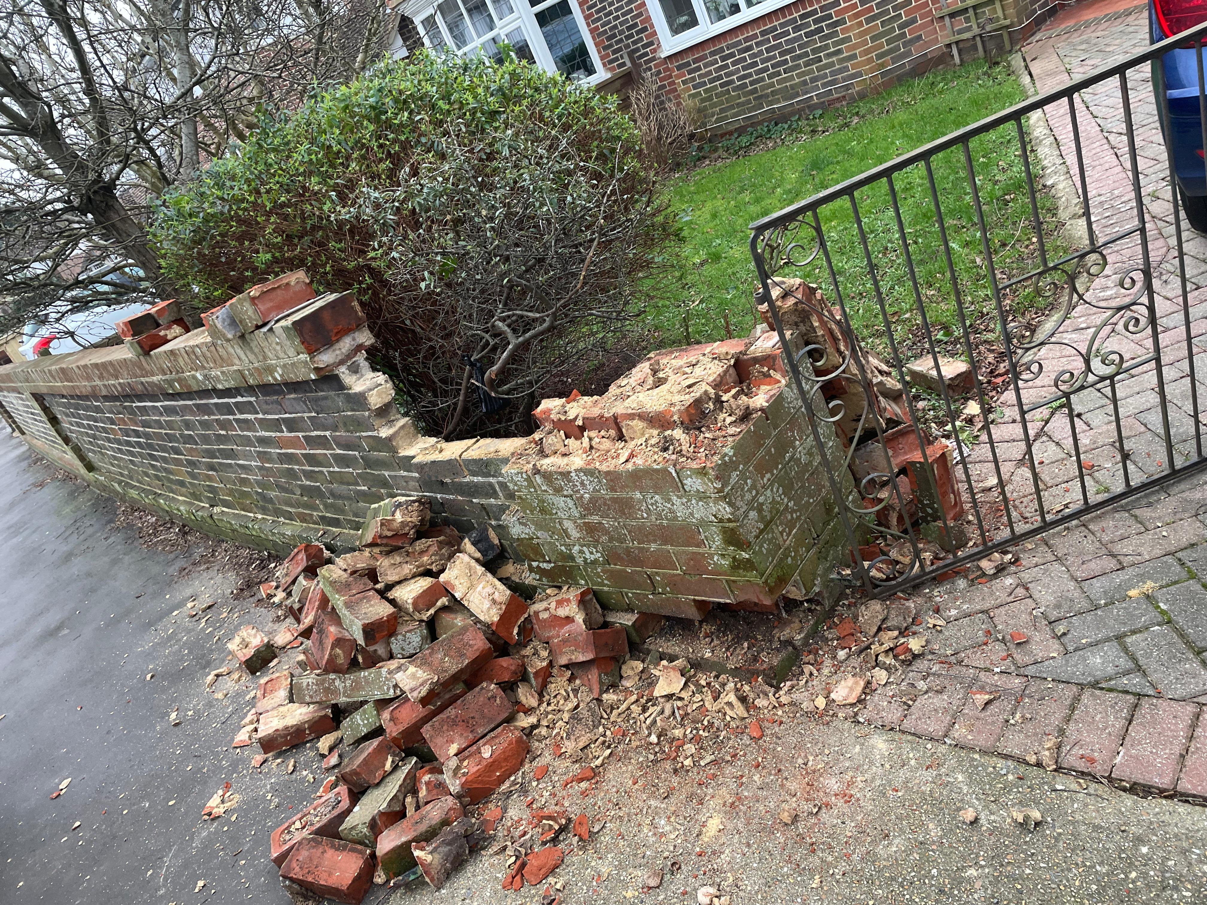 Collapsed front garden brick wall with scattered bricks